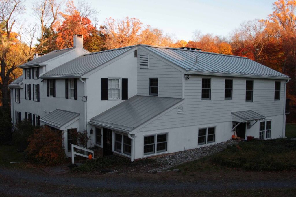 white 1820 Chester County Farmhouse with Galvalume standing seamed roofing, James Hardie siding and chimney repair